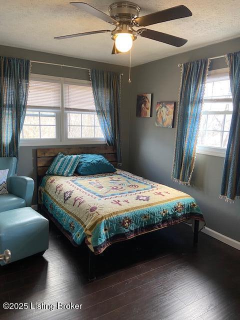 bedroom with a textured ceiling, a ceiling fan, baseboards, and wood finished floors