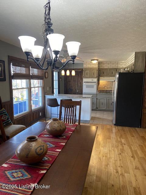 dining room featuring an inviting chandelier, light wood finished floors, and a textured ceiling