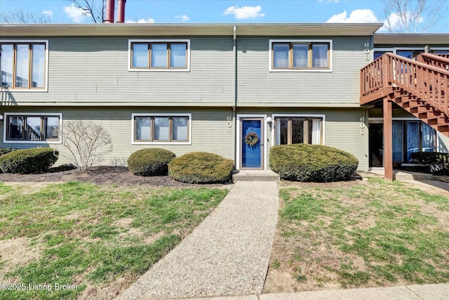 view of front of home with stairway, a deck, and a front yard