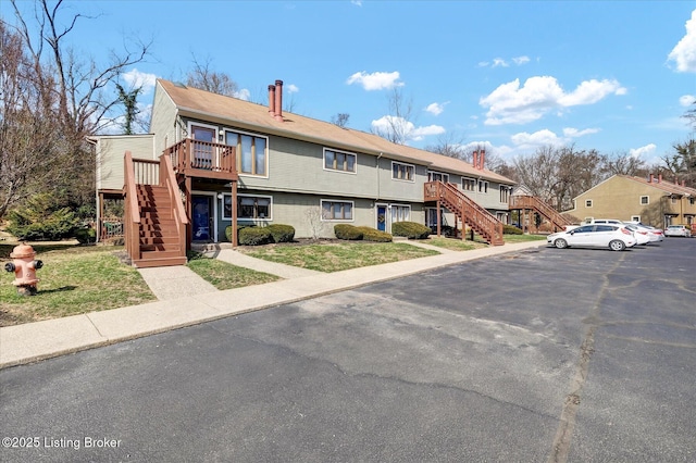 exterior space featuring stairway, a chimney, and uncovered parking