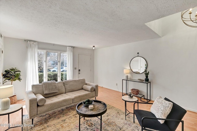 living area with a textured ceiling, baseboards, and wood finished floors