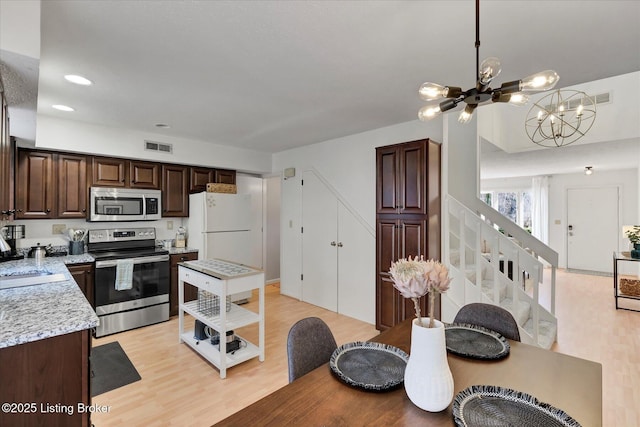 kitchen featuring a notable chandelier, a sink, appliances with stainless steel finishes, light countertops, and dark brown cabinets