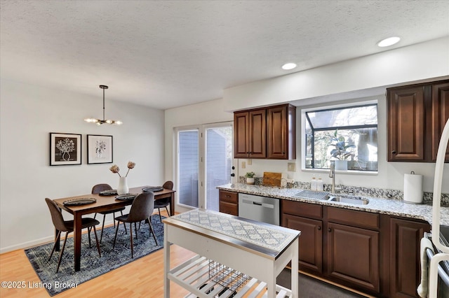 kitchen featuring light wood-style flooring, a sink, a textured ceiling, an inviting chandelier, and dishwasher