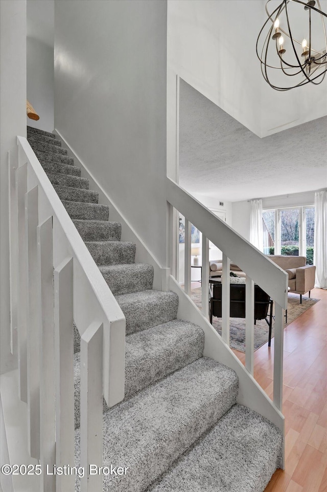 stairway featuring an inviting chandelier and wood finished floors