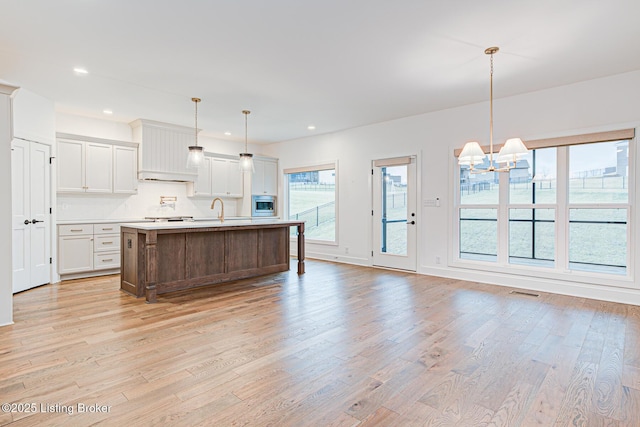 kitchen featuring an island with sink, recessed lighting, light countertops, and light wood-style floors