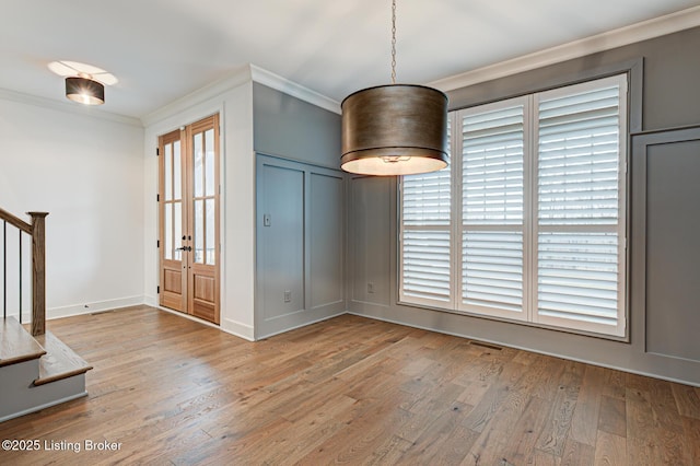 foyer entrance featuring light wood finished floors, visible vents, crown molding, baseboards, and stairway