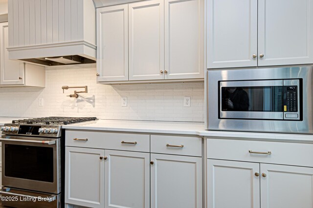 kitchen featuring tasteful backsplash, stainless steel appliances, light countertops, and custom range hood