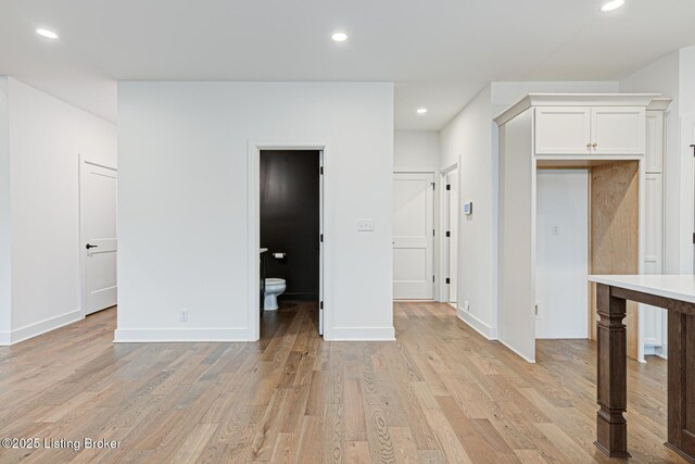 interior space with light wood-style flooring, recessed lighting, baseboards, and white cabinets