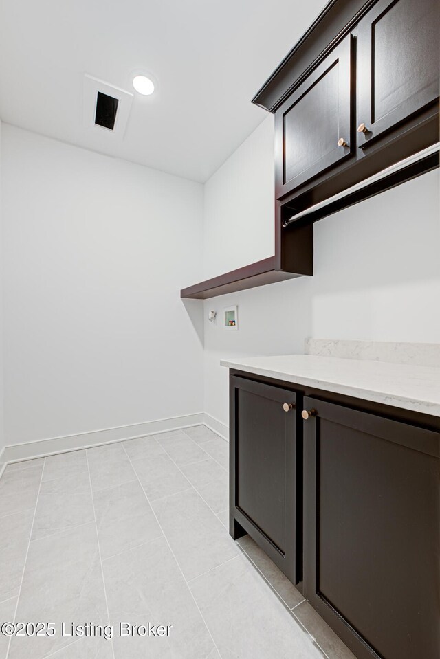 kitchen featuring dark brown cabinets, visible vents, baseboards, and light tile patterned floors