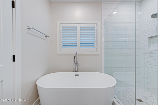 full bathroom with a tile shower and a freestanding bath