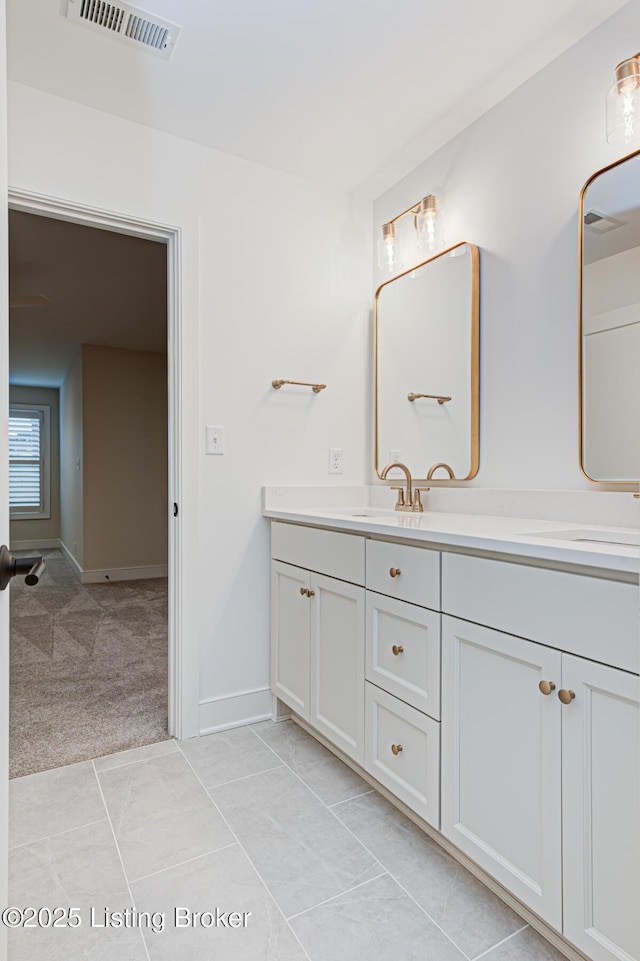 bathroom featuring a sink, visible vents, baseboards, and double vanity