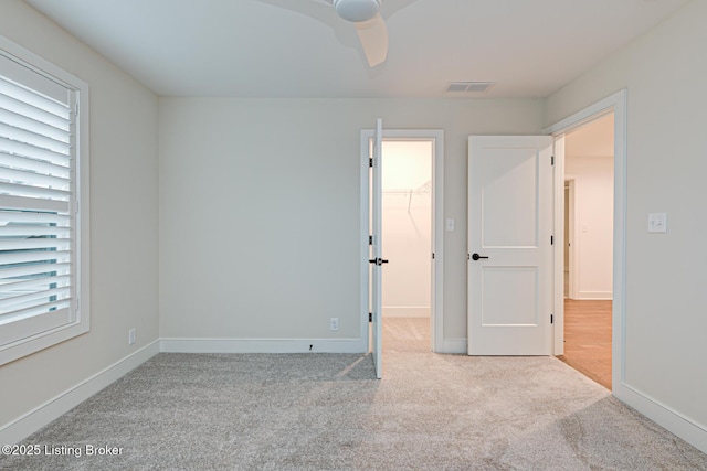 unfurnished bedroom featuring a ceiling fan, baseboards, carpet, and a spacious closet