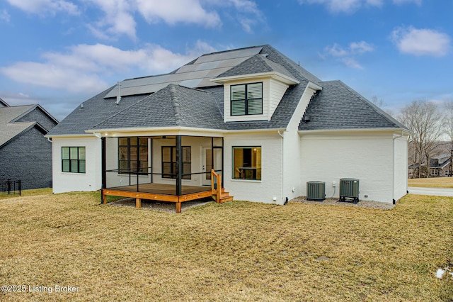 rear view of property with cooling unit, a lawn, and roof with shingles