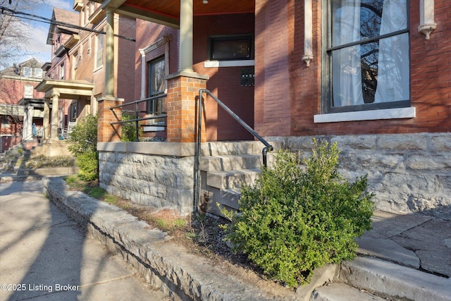 view of side of home with a porch and brick siding