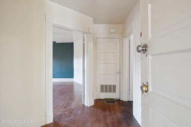 corridor featuring wood finished floors, visible vents, and baseboards