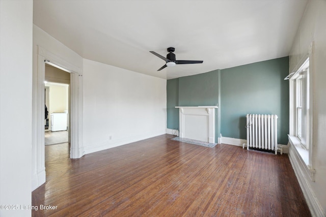 spare room featuring baseboards, wood finished floors, ceiling fan, and radiator heating unit