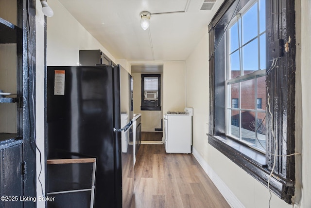 kitchen featuring visible vents, baseboards, freestanding refrigerator, wood finished floors, and washer / clothes dryer