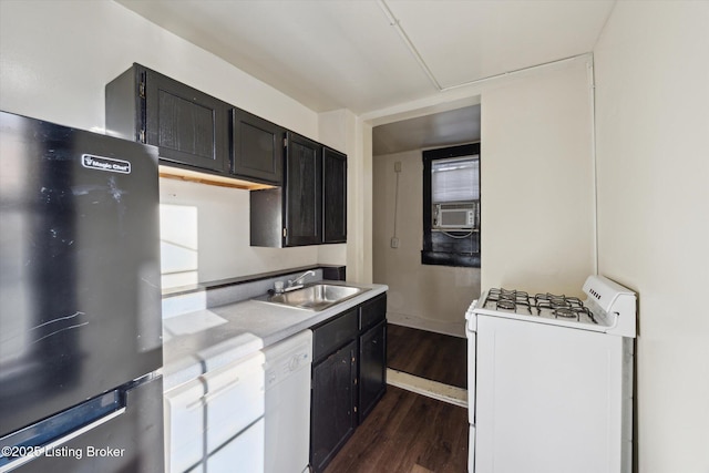 kitchen with a sink, dark cabinets, light countertops, white appliances, and dark wood-style flooring