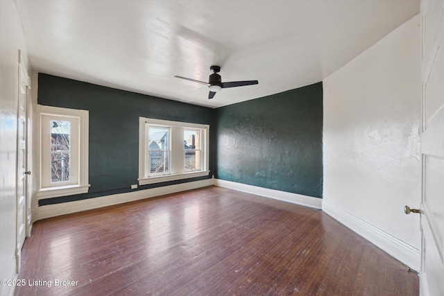 empty room featuring baseboards, wood finished floors, a ceiling fan, and a textured wall