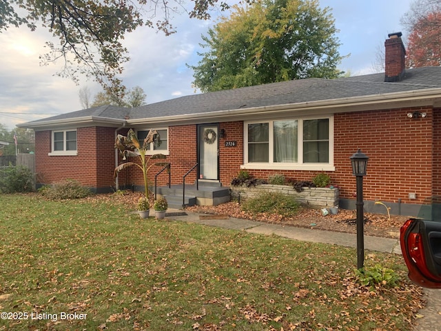 ranch-style home with a front lawn, brick siding, and a chimney