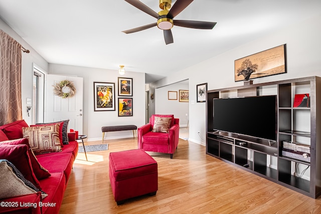 living room featuring baseboards, a ceiling fan, and wood finished floors