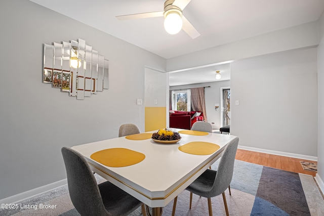 dining space with a ceiling fan, light wood-style floors, and baseboards