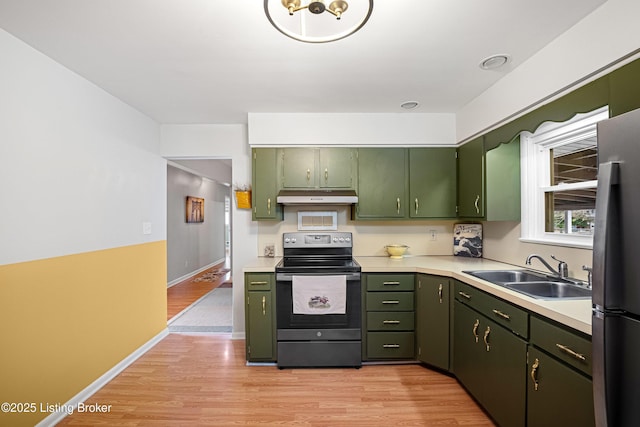 kitchen with under cabinet range hood, green cabinetry, light countertops, appliances with stainless steel finishes, and a sink