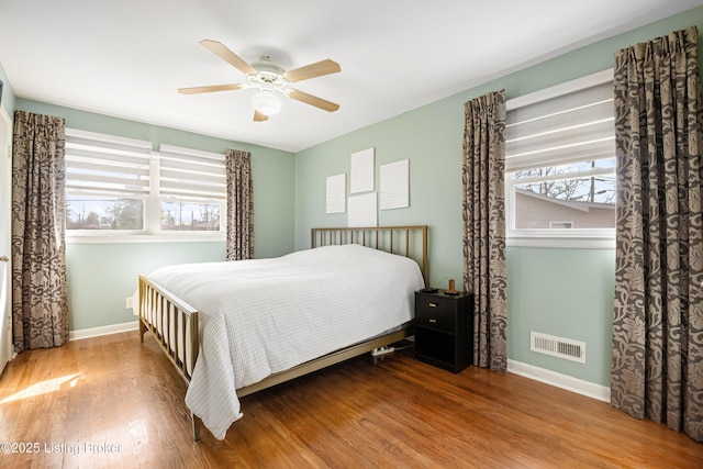 bedroom with multiple windows, baseboards, and wood finished floors