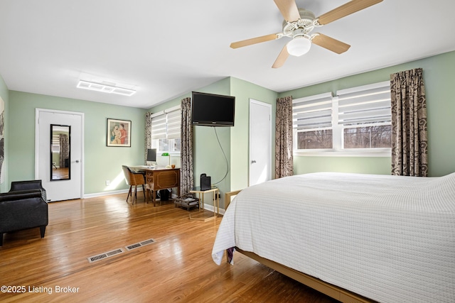 bedroom featuring a ceiling fan, visible vents, wood finished floors, and baseboards