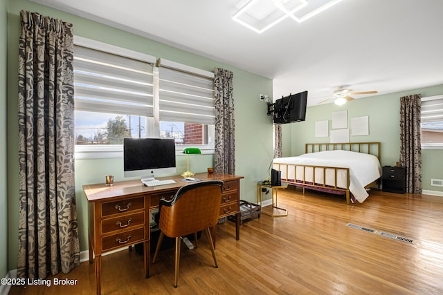 bedroom featuring visible vents, ceiling fan, baseboards, and wood finished floors