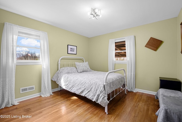 bedroom featuring visible vents, baseboards, and wood finished floors