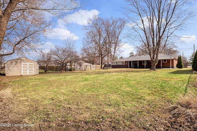 view of yard featuring a storage unit, an outdoor structure, and fence