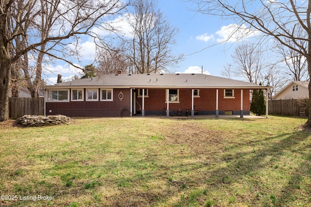 back of property with a yard, a patio, brick siding, and fence