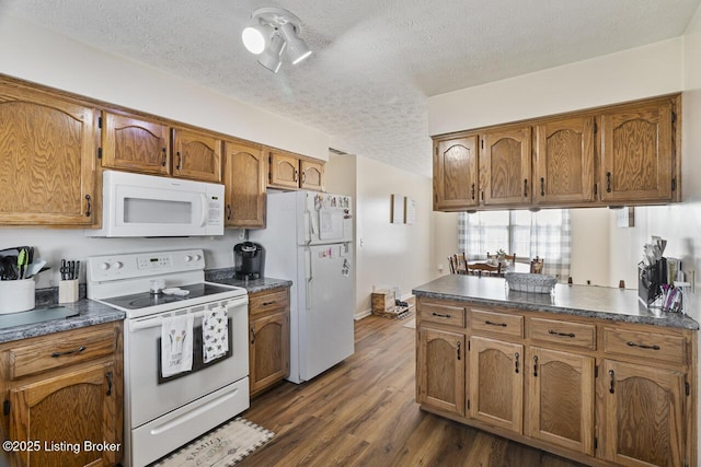 kitchen with dark countertops, white appliances, and brown cabinetry