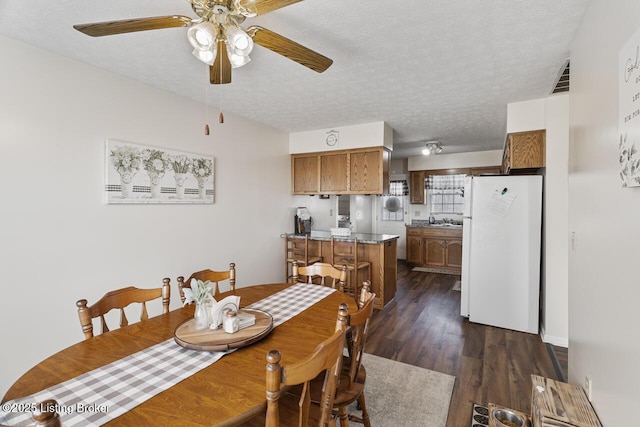 dining space featuring visible vents, a textured ceiling, ceiling fan, and dark wood-style flooring