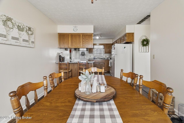 dining room featuring visible vents, a textured ceiling, and baseboards