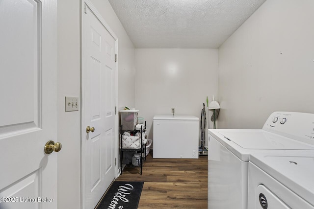 washroom with washer and dryer, laundry area, dark wood finished floors, and a textured ceiling