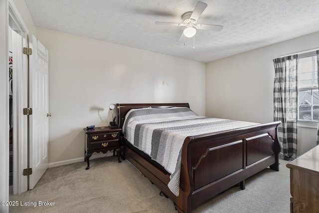 bedroom with light carpet, baseboards, a textured ceiling, and a ceiling fan