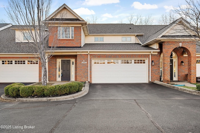 view of front facade featuring brick siding, an attached garage, driveway, and a shingled roof