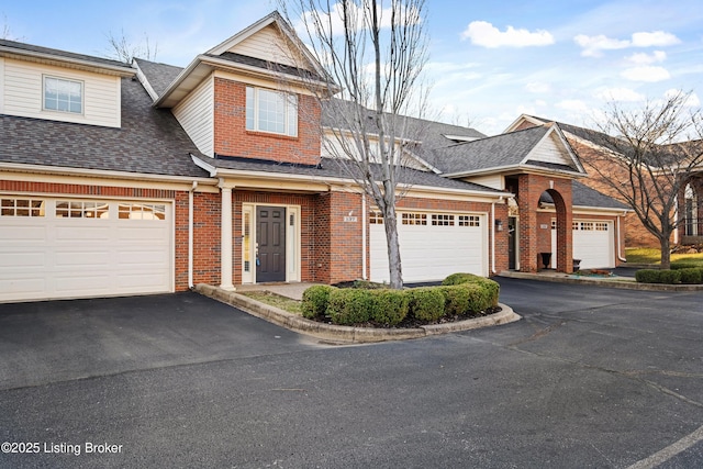 view of front of house with an attached garage, brick siding, driveway, and roof with shingles