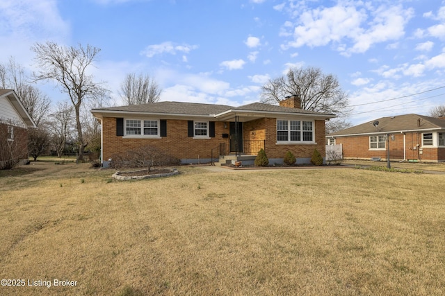 ranch-style home with brick siding, a chimney, a front yard, and roof with shingles