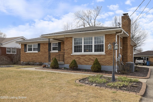 view of front of house with a front lawn, cooling unit, roof with shingles, brick siding, and a chimney