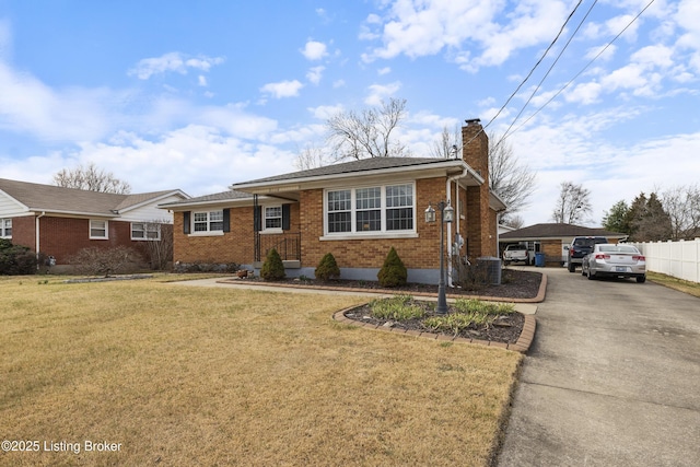 ranch-style house featuring a front yard, fence, driveway, a chimney, and brick siding