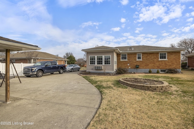 exterior space with fence, brick siding, roof with shingles, and a lawn