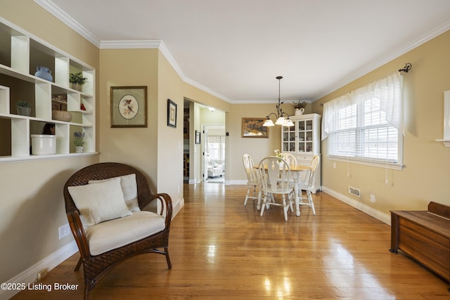 dining space with baseboards, an inviting chandelier, wood finished floors, and crown molding