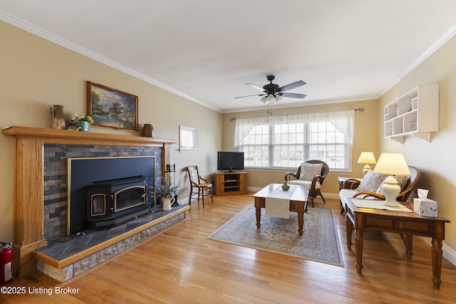 living area featuring a ceiling fan, crown molding, baseboards, and wood finished floors