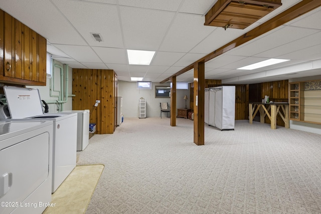 laundry room with visible vents, light carpet, washer and clothes dryer, wood walls, and laundry area