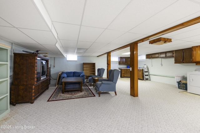 living area with light carpet, washer / clothes dryer, and a paneled ceiling