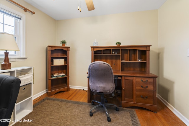 office space with baseboards, wood finished floors, and a ceiling fan