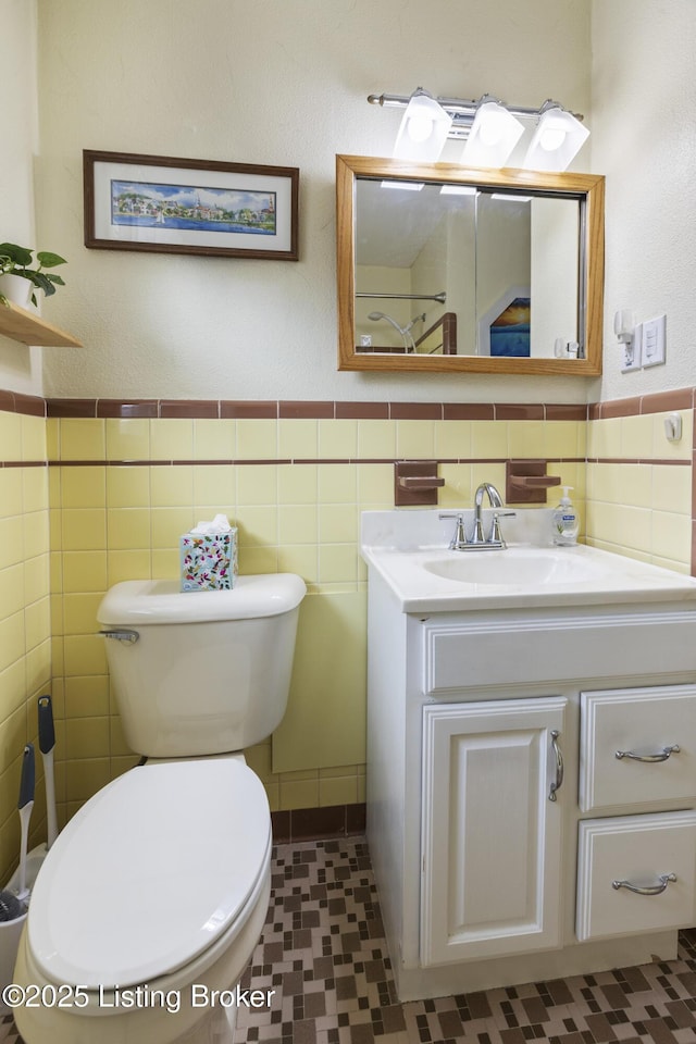 bathroom featuring vanity, tile walls, toilet, and wainscoting